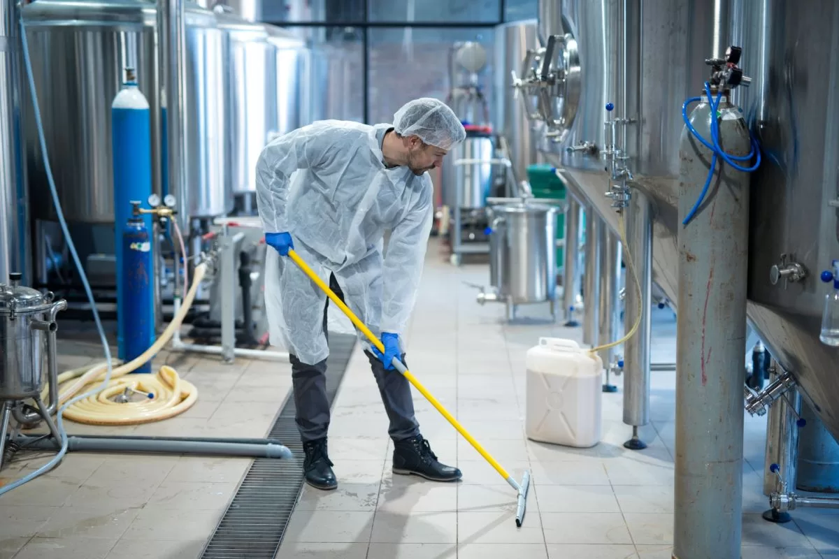 pulizia industriale e sanificazione__ Tecnico con tuta protettiva sanifica linea produttiva alimentare